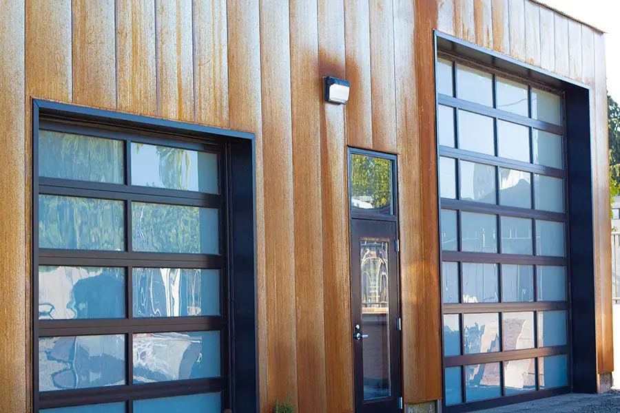 Black framed glass overhead doors on a wood-clad commercial building