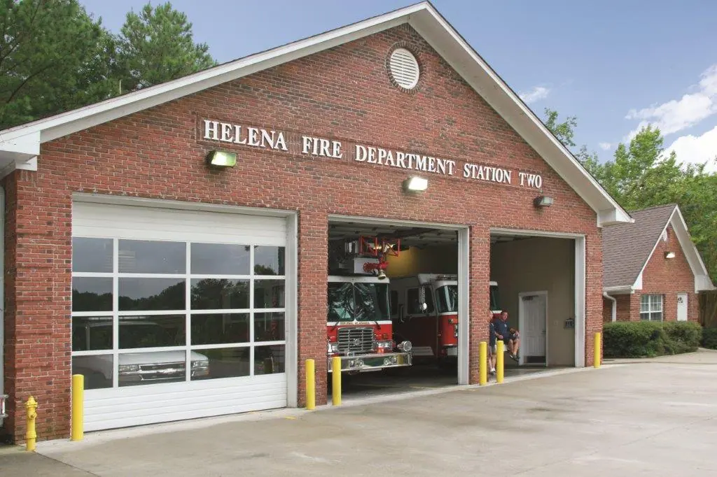 A brick fire station with glass-paneled overhead doors