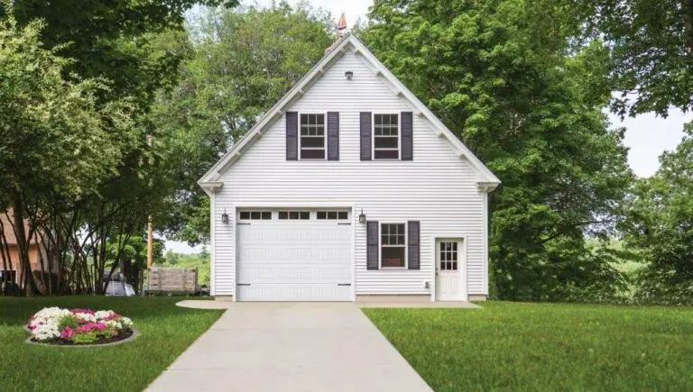 A white garage with a single garage door at the end of a driveway
