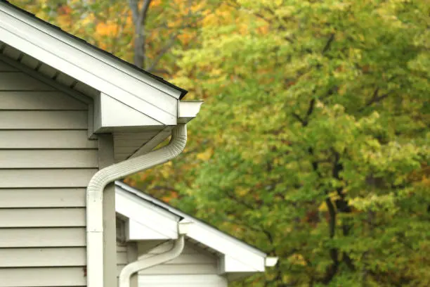 A white gutter and downspout on the corner of a home