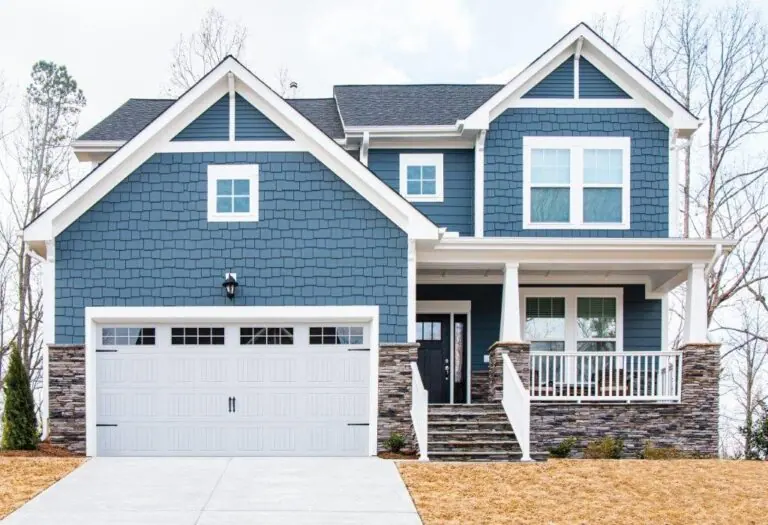 White raised-panel garage door with windows on a blue two-storey home